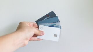 複数のクレジットカードを手に持つ様子。楽天カードをはじめとしたカード活用で楽天経済圏のポイント還元率を高められる